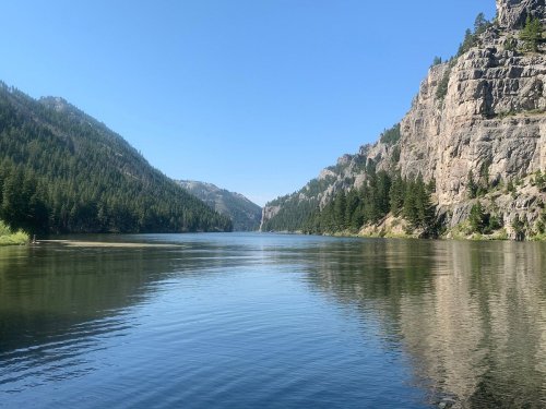 A serene lake surrounded by mountains and lush greenery under a clear blue sky.