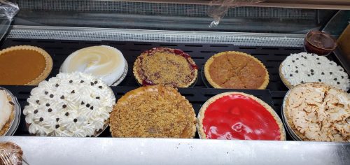 A display of various pies and desserts, including pumpkin, cherry, and cream-topped options.