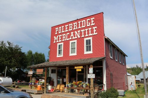 Red building with "Polebridge Mercantile" sign, featuring a bakery and colorful flowers outside.