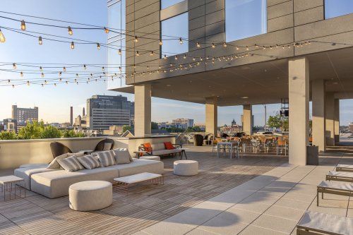 Rooftop terrace with modern seating, string lights, and city skyline views during sunset.