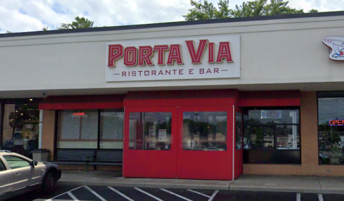 Exterior of Porta Via Ristorante e Bar, featuring a red entrance and signage, located in a shopping plaza.
