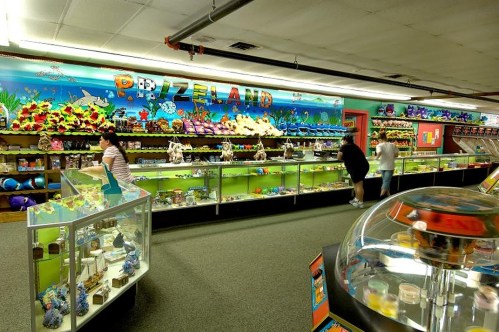 A colorful store interior filled with various toys and crafts, featuring display cases and a vibrant mural.