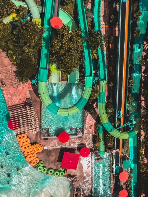 Aerial view of colorful water slides and a pool area with orange inner tubes and red umbrellas.