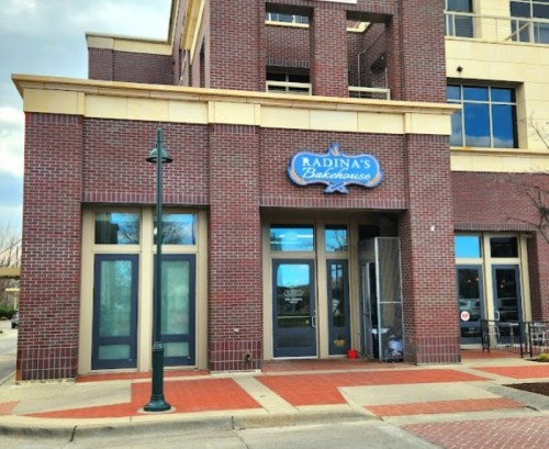 Exterior of Radina's Bakehouse, featuring a brick facade and large windows, with a streetlamp in front.