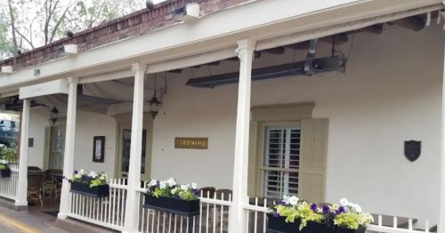 Exterior of a building with a sign reading "Geronimo," featuring flower boxes and a porch with seating.