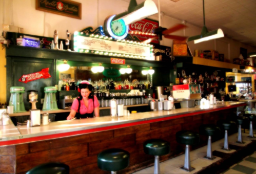 A vintage diner with a woman at the counter, retro decor, and a Coca-Cola sign, featuring green stools and a nostalgic vibe.
