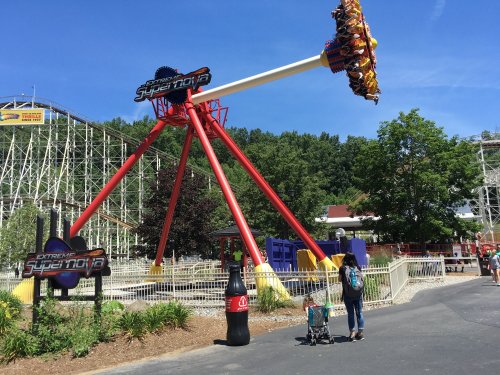 A thrill ride named "Supernova" at an amusement park, with a family walking nearby and trees in the background.