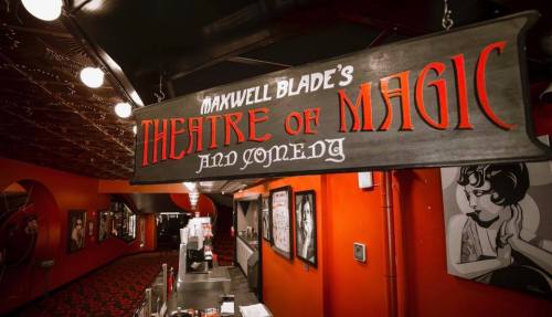 Sign for "Maxwell Blade's Theatre of Magic and Comedy" in a vibrant, red-themed interior.