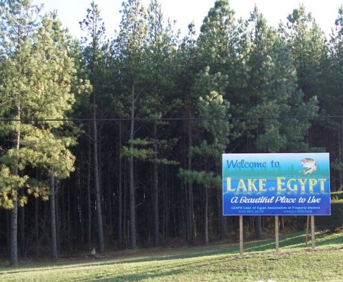 A welcome sign for Lake of Egypt, surrounded by tall pine trees, promoting it as a beautiful place to live.