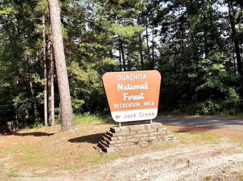 Sign for Ouachita National Forest Recreation Area, directing to Jack Creek, surrounded by trees.