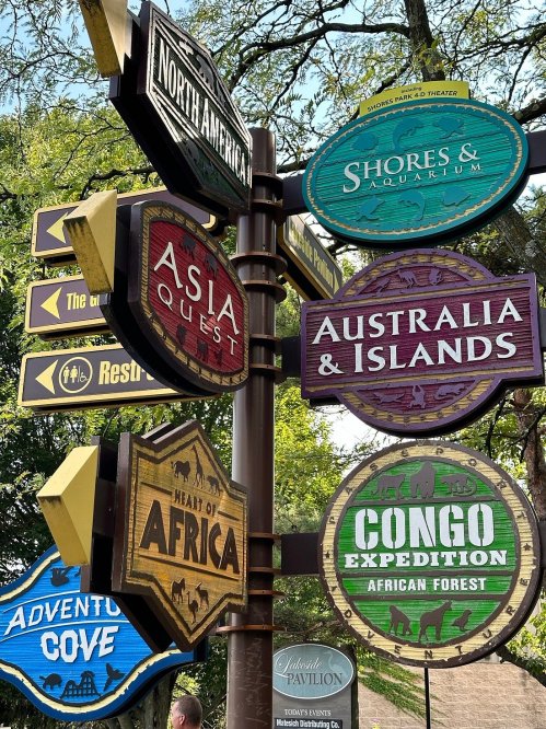 A signpost with directional signs for various attractions: North America, Asia Quest, Australia, Africa, and Congo Expedition.