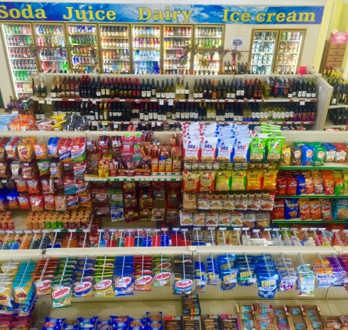 A colorful display of snacks, drinks, and dairy products in a convenience store aisle.