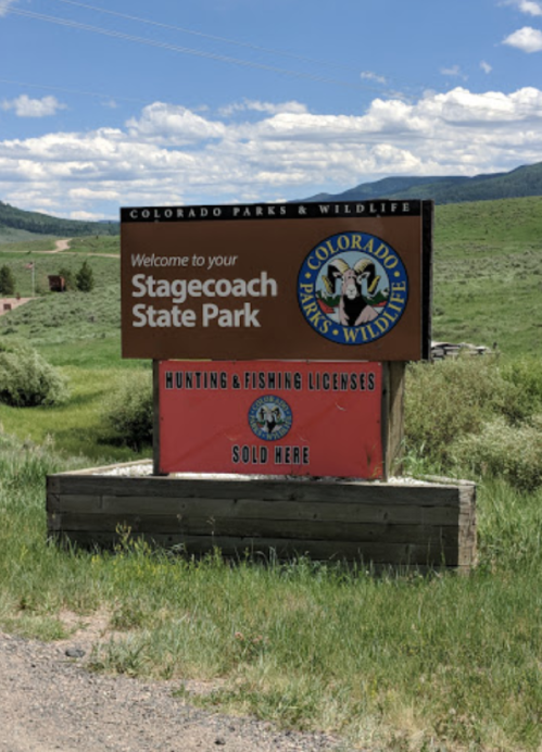 Sign welcoming visitors to Stagecoach State Park, featuring Colorado Parks & Wildlife logo and information on licenses.