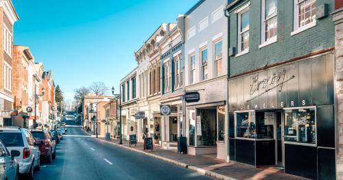 A charming street lined with shops and parked cars, featuring a jeweler's storefront on a sunny day.