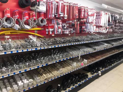 A hardware store aisle filled with various plumbing supplies, including pipes, fittings, and hoses on display.