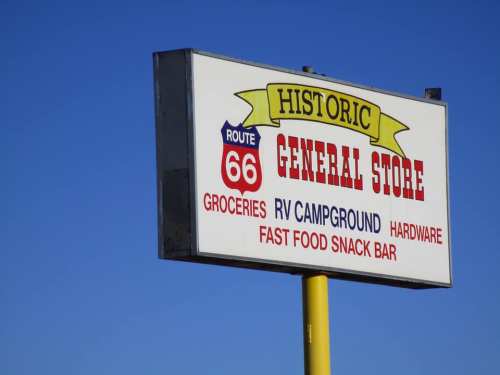 Sign for a historic general store on Route 66, listing groceries, RV campground, hardware, and snack bar services.