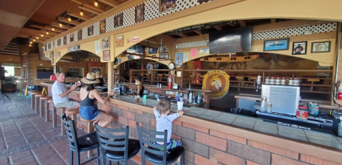 A family sits at a bar in a lively restaurant, enjoying drinks and snacks in a warm, inviting atmosphere.