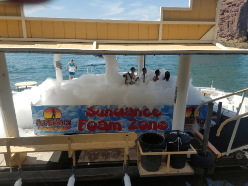 A foam zone at Sundance with children playing in white foam on a sunny day by the water.