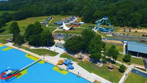 Aerial view of a water park featuring slides, a pool, and grassy areas with trees in the background.