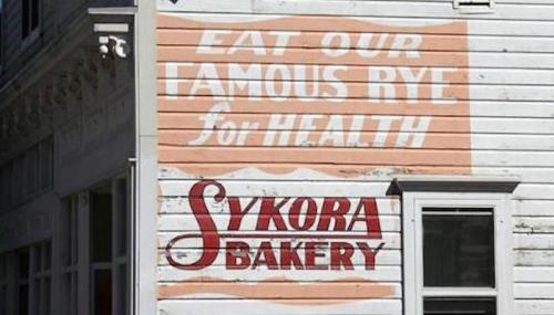 Faded sign on a building promoting Sykora Bakery and its famous rye bread for health.
