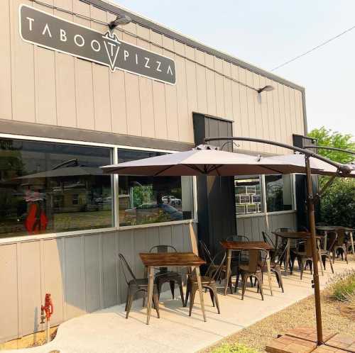 Exterior of Taboo Pizza with outdoor seating under umbrellas on a sunny day.