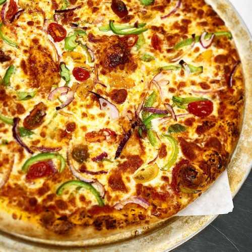 A freshly baked pizza topped with cheese, tomatoes, green peppers, and onions on a golden crust.