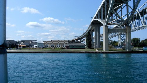 View of a bridge spanning over water, with buildings along the shore under a clear blue sky.