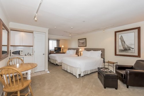 A cozy hotel room featuring two beds, a small dining table, and a kitchenette area with a microwave.