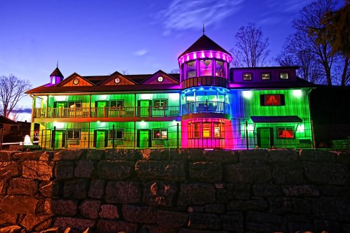 A colorful building illuminated with vibrant lights at dusk, featuring multiple levels and a unique architectural design.