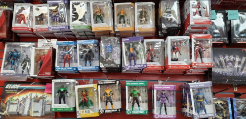A display of various action figures in packaging, featuring superheroes and villains from different franchises.