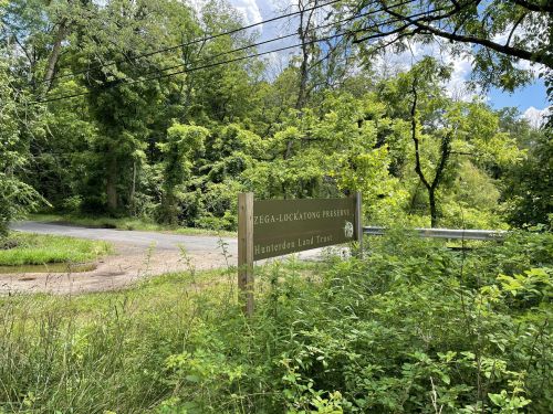 A sign for the Zega-Lookout Preserve by the Hunterdon Land Trust, surrounded by greenery and trees.