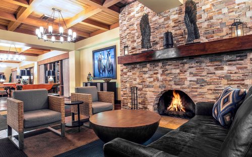 Cozy lobby with a stone fireplace, modern seating, and warm lighting, creating a welcoming atmosphere.