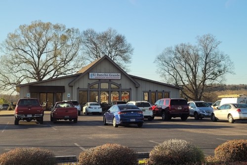 Exterior of El Rancho Grande restaurant with parked cars and trees in the background on a clear day.