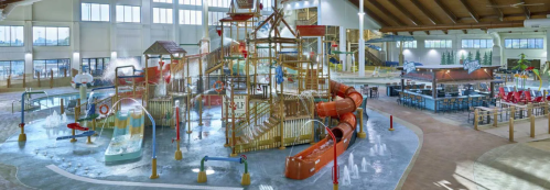 Indoor water park featuring a large play structure, water slides, and various water features. Bright and spacious environment.