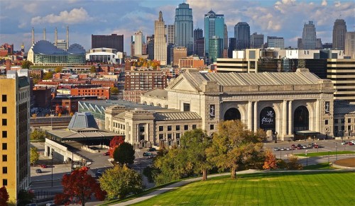 Aerial view of Kansas City, featuring Union Station and a skyline of modern buildings against a blue sky.