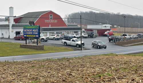 A red barn-style building with a sign for Dietrich's Meats and Country Store, surrounded by parked cars and fields.