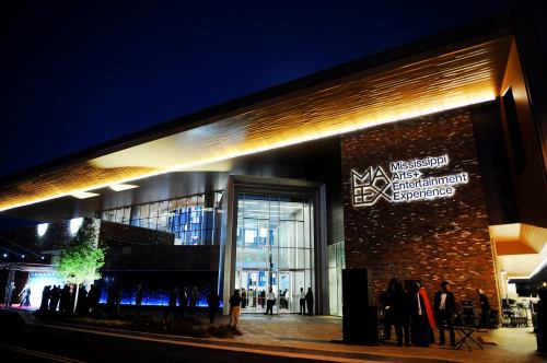 Exterior of the Mississippi Arts and Entertainment Experience building at night, featuring modern architecture and lighting.