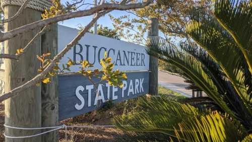 Sign for Buccaneer State Park surrounded by greenery and trees.