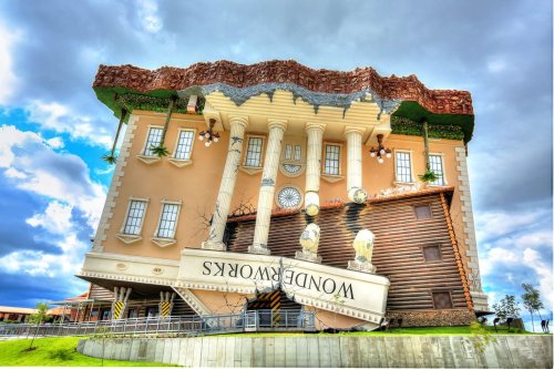 A whimsical building with an upside-down design, featuring columns and a slanted roof, labeled "Wonderworks."