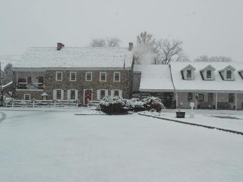 A snowy scene featuring a stone building and a nearby structure, both surrounded by a white landscape.