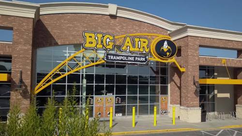 Exterior of Big Air Trampoline Park, featuring a large sign and glass entrance, set against a clear blue sky.