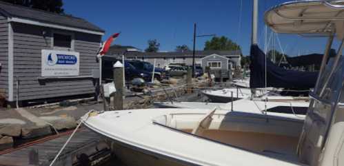 A marina scene with boats docked, a building in the background, and clear blue skies.