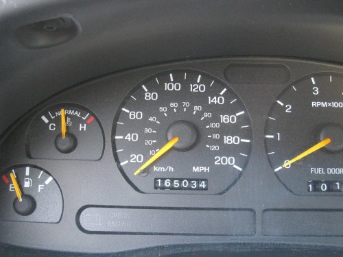 Dashboard of a car showing speedometer, fuel gauge, and odometer reading 165034 miles.