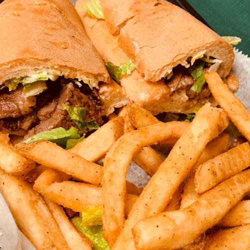 Two sandwiches filled with meat and lettuce, served with a side of crispy French fries on a paper tray.
