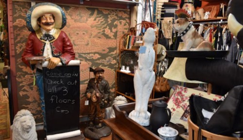 A quirky antique shop filled with various collectibles, including a cowboy statue, a dog figure, and decorative items.