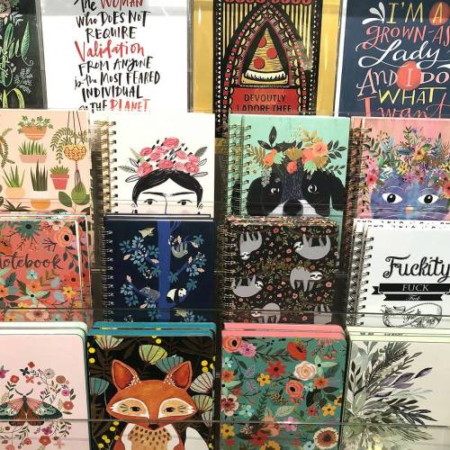 A colorful display of various notebooks featuring floral, animal, and artistic designs on their covers.