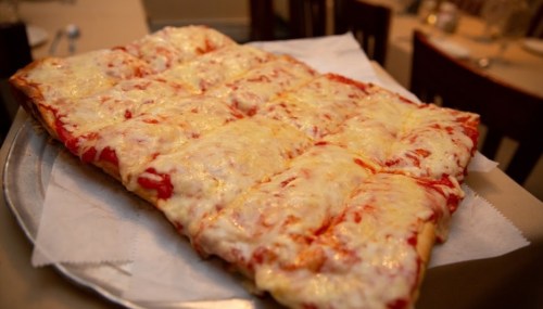 A rectangular pizza topped with melted cheese and tomato sauce, served on a silver platter.