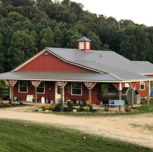 A red barn-style building with a metal roof, surrounded by greenery and decorated with bunting.