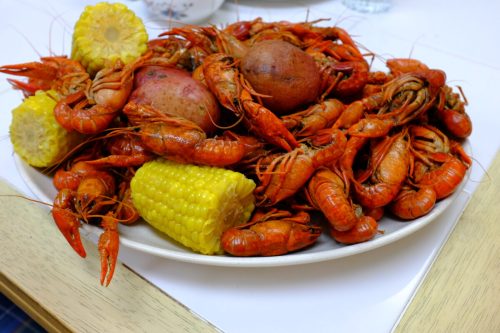A large platter of boiled crawfish, red potatoes, and corn on the cob, arranged appetizingly.