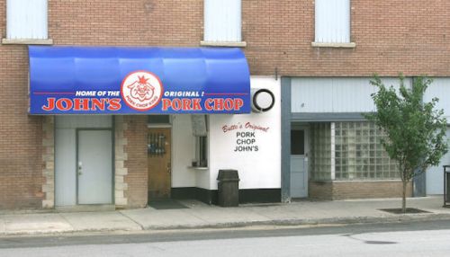Exterior of a restaurant with a blue awning reading "John's Original Pork Chop" and a brick facade.